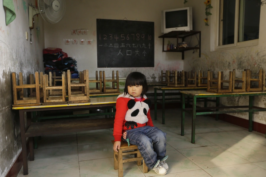 A girl sits on a chair in a class at a kindergarten, a school for children of migrant workers, on the outskirts of Beijing November 8, 2013.