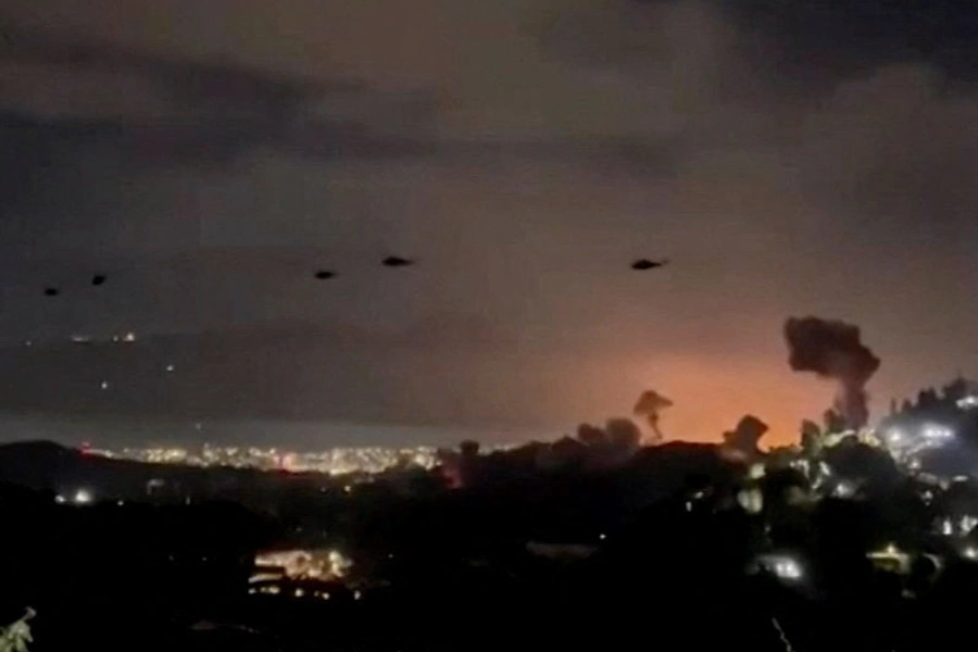 Helicopters fly past plumes of smoke rising from explosions in Caracas, Venezuela, January 3, 2026.
