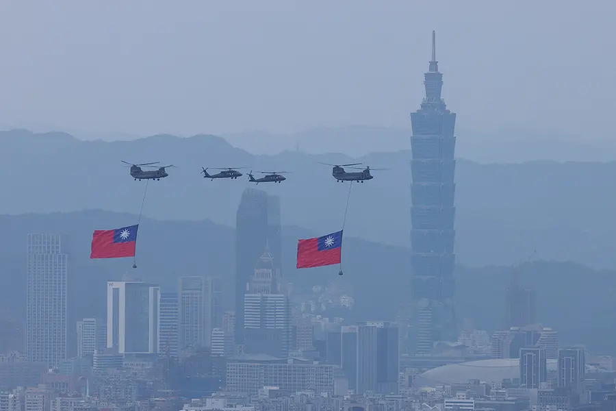 Military helicopters hang Taiwanese flags above a foggy cityscape.
